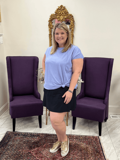 Curvy model wearing blue pima swoop tee with a black active skort and tennis shoes